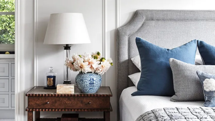 A country style bedroom with wainscoting and vintage-style furniture.