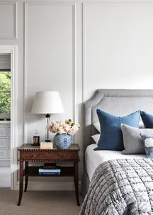 A country style bedroom with wainscoting and vintage-style furniture.