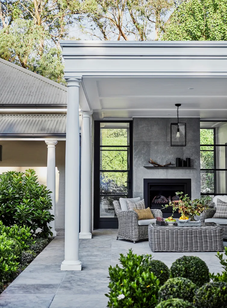 An undercover outdoor seating area with a fireplace and wicker furniture.