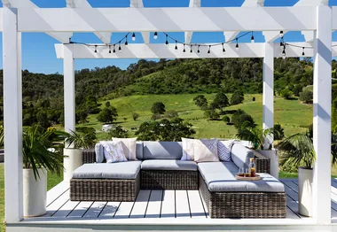 a modern outdoor sitting area on a sunny day with a green hills view