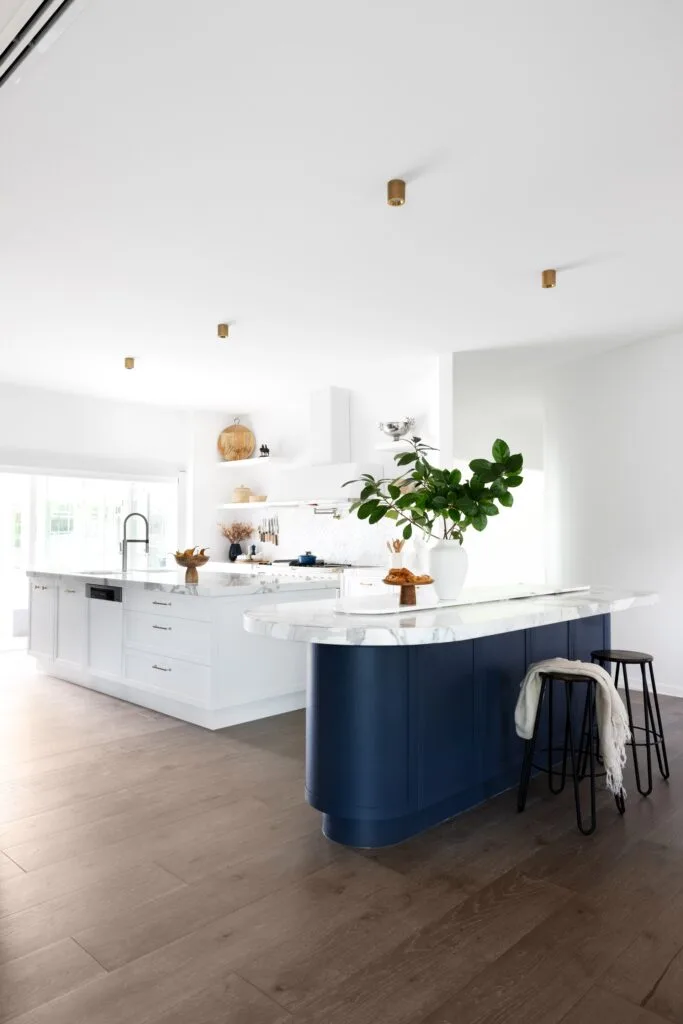 A modern country kitchen with a marble island and shaker cabinets.