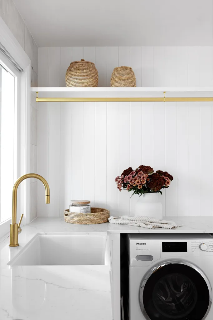 A classic white laundry with white stone benchtops and gold hardware.