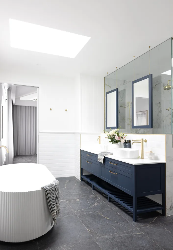 A modern country ensuite with a freestanding fluted bath and blue vanity.