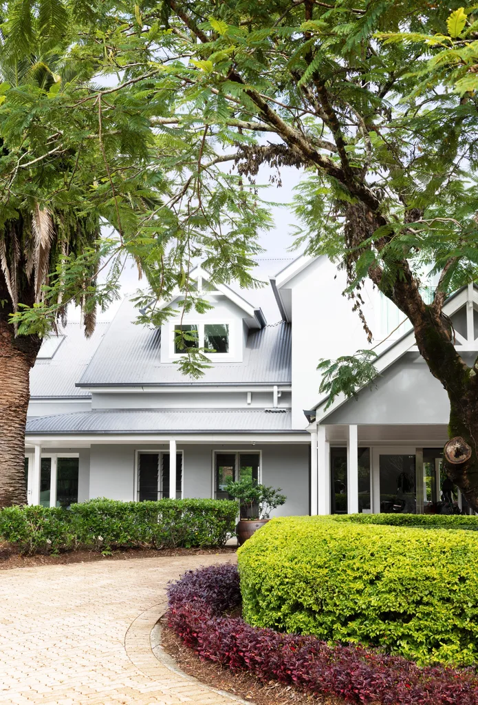 A modern country house with rounded hedges and trees.