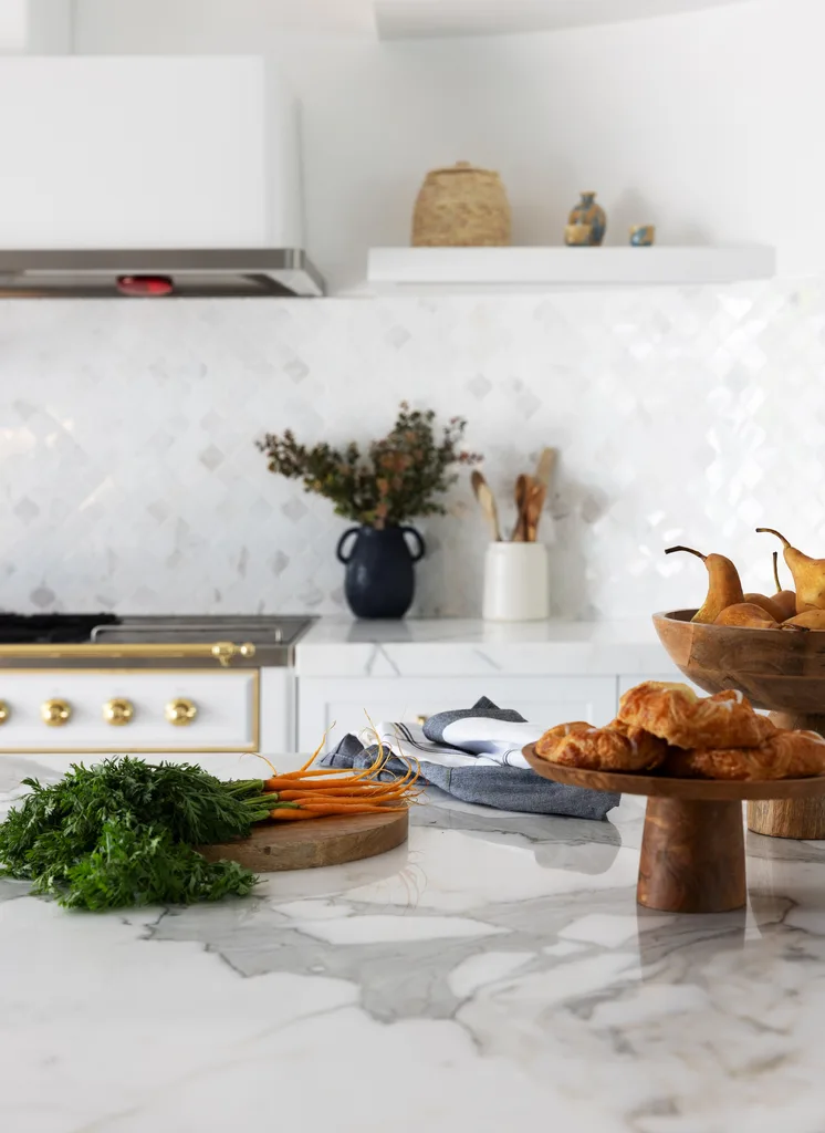 A marble-topped kitchen island and bowls of fruit and pastries.