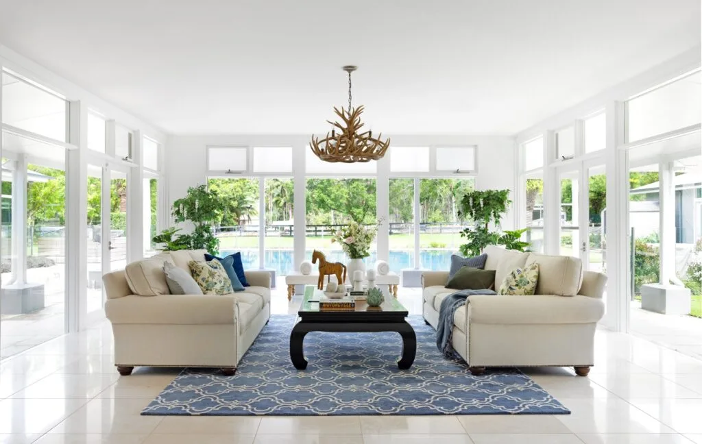 A modern country living room with white and blue furnishings overlooking the pool.