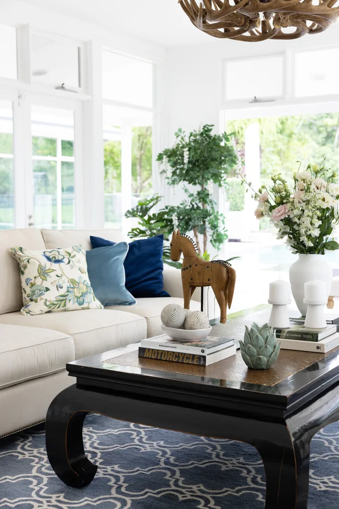 A timber coffee table with a decorative horse beside a white sofa.