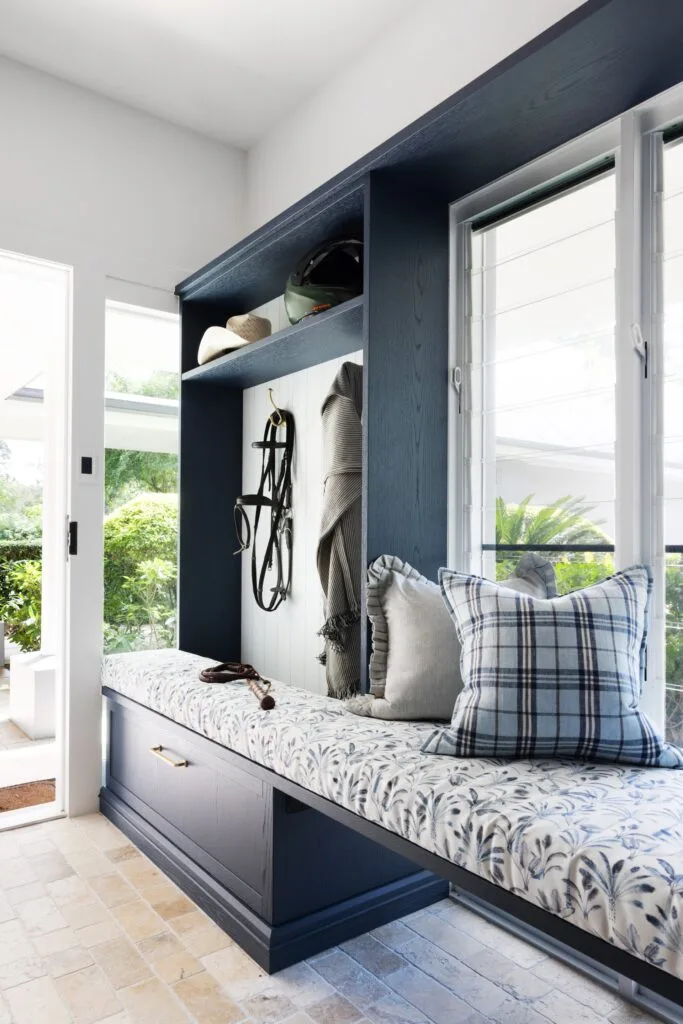 A classic blue mudroom with an upholstered bench.