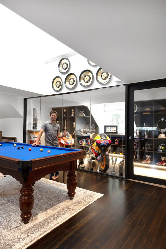 Casey Stoner in the trophy room beside a pool table.