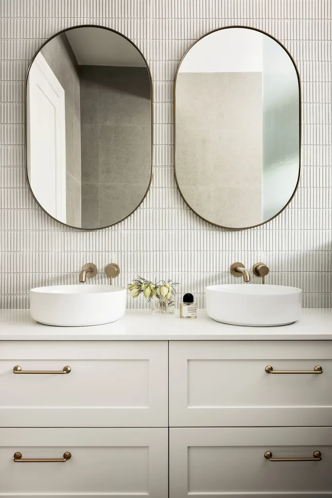 A double vanity with a kit kat tile splashback and oval mirrors.