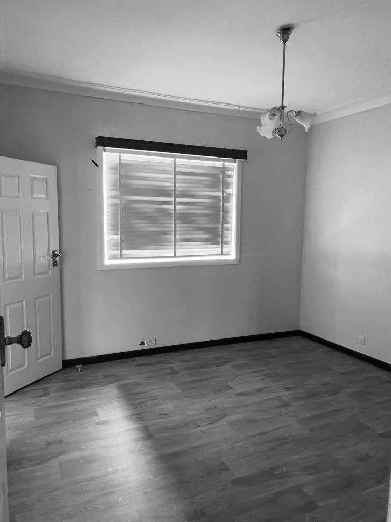 A dark bedroom with linoleum-style flooring and horizontal blinds.