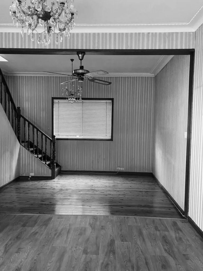 A dated living room area with striped wallpaper and chandeliers.