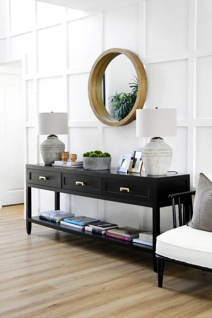 A dark timber console and a round timber mirror above.