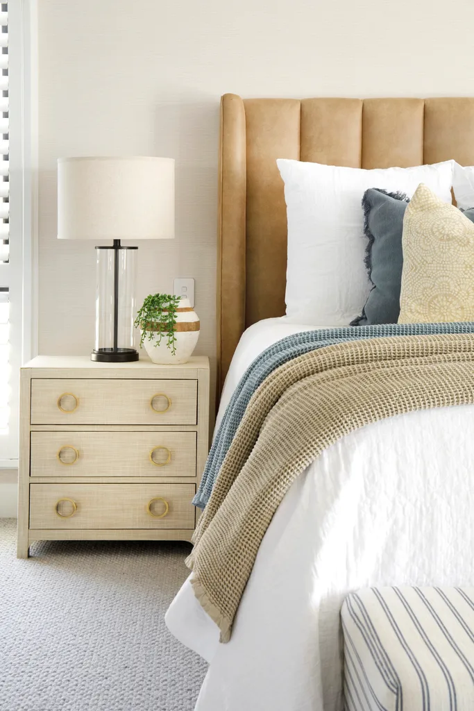 A main bedroom with a leather bedhead and side drawers.