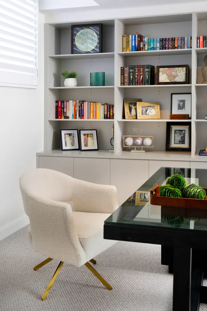 An open-plan office with a white armchair and glass desk.