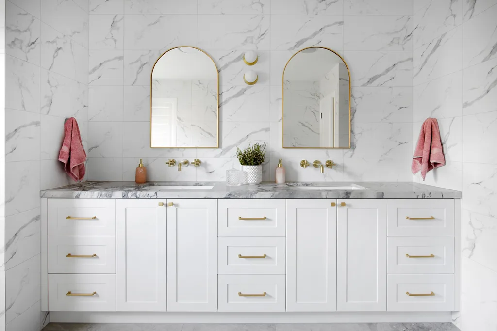 A modern all-white bathroom with a marble-topped double vanity.