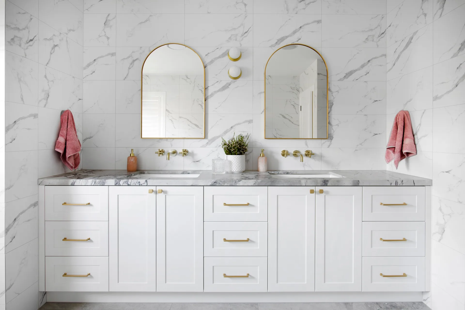 A modern all-white bathroom with a marble-topped double vanity.