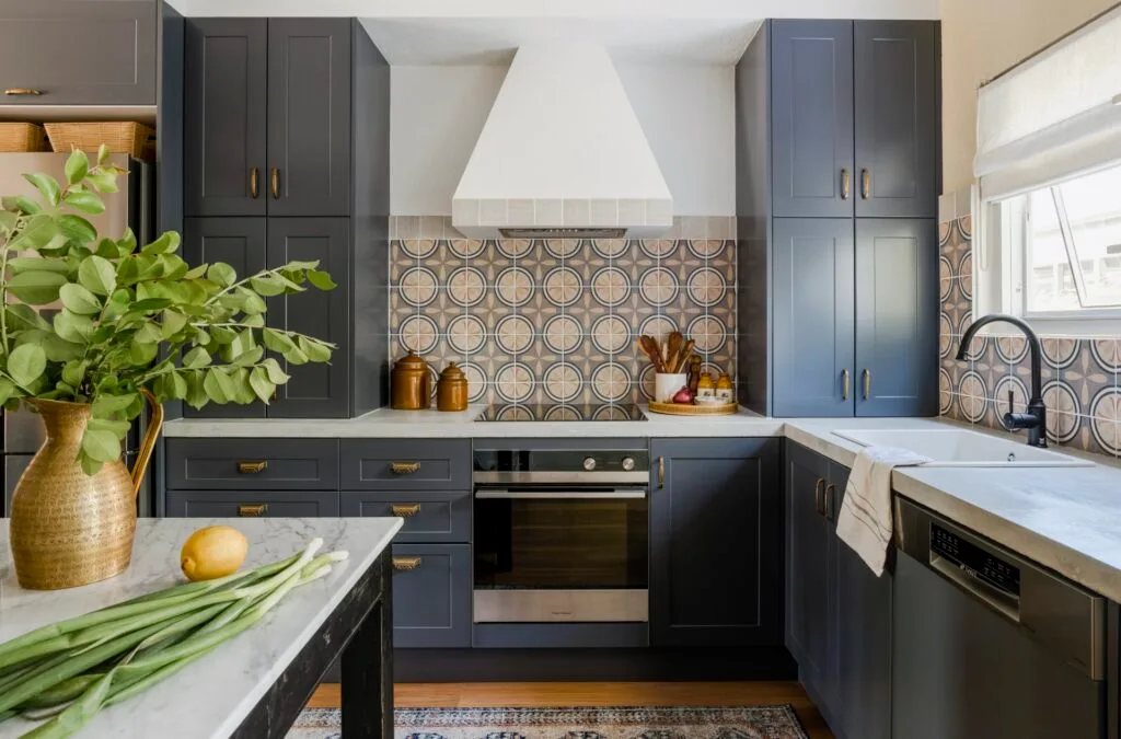 A modern kitchen with blue cabinetry, mosaic splashback tiles and marble benchtops.