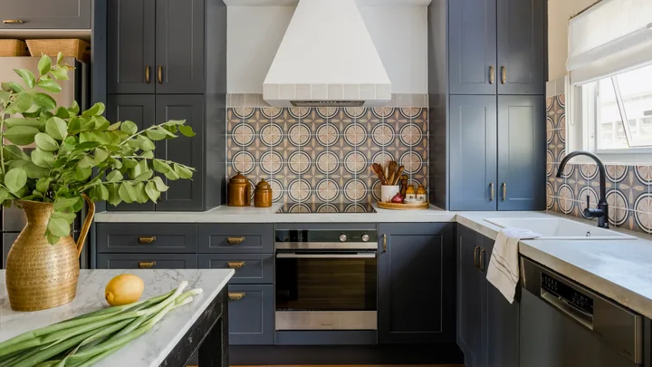 A modern kitchen with blue cabinetry, mosaic splashback tiles and marble benchtops.