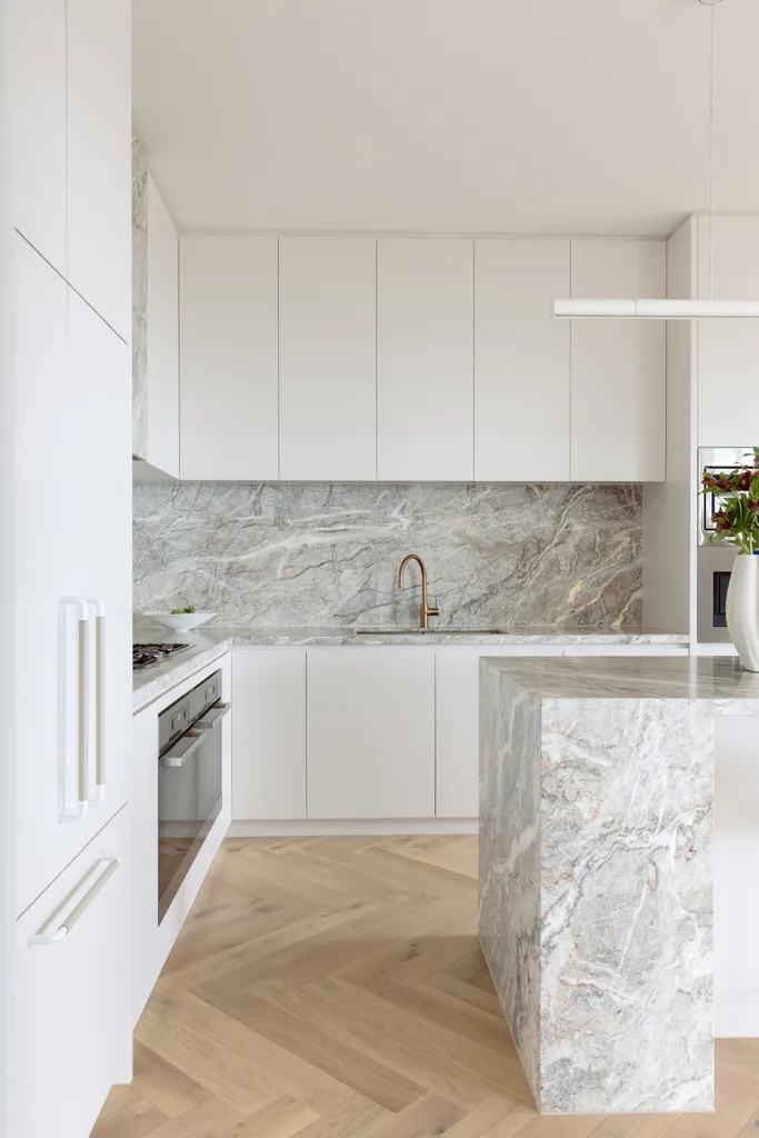 White kitchen cabinetry over grey marble benchtops.