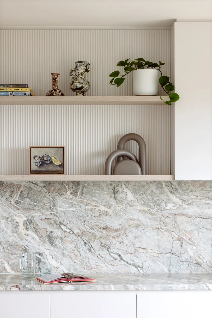 A grey marble splashback below open timber shelving.