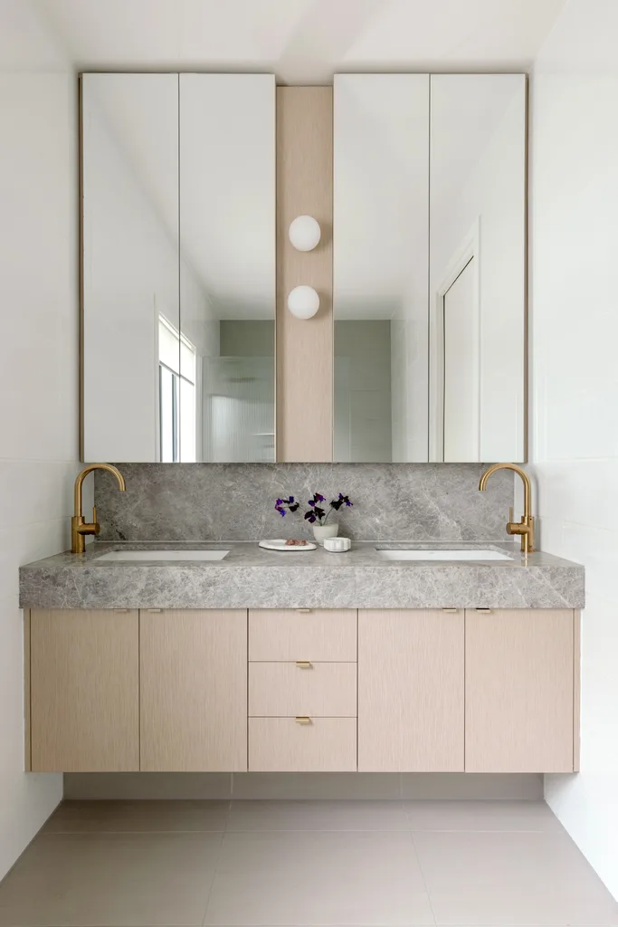 A modern ensuite with a floating vanity topped with grey stone.