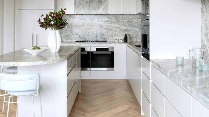 A kitchen with herringbone timber floors and grey marble details.