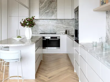 A kitchen with herringbone timber floors and grey marble details.