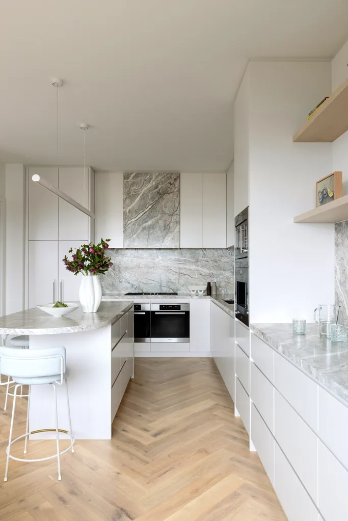 A kitchen with herringbone timber floors and grey marble details.