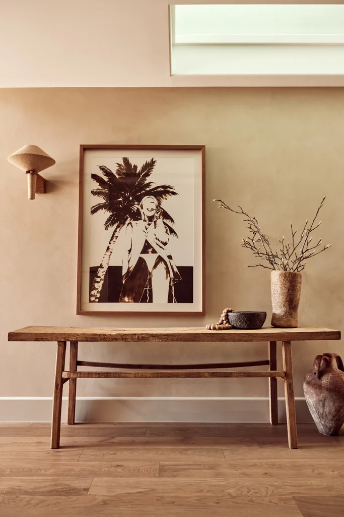 A timber console below a framed tropical portrait.