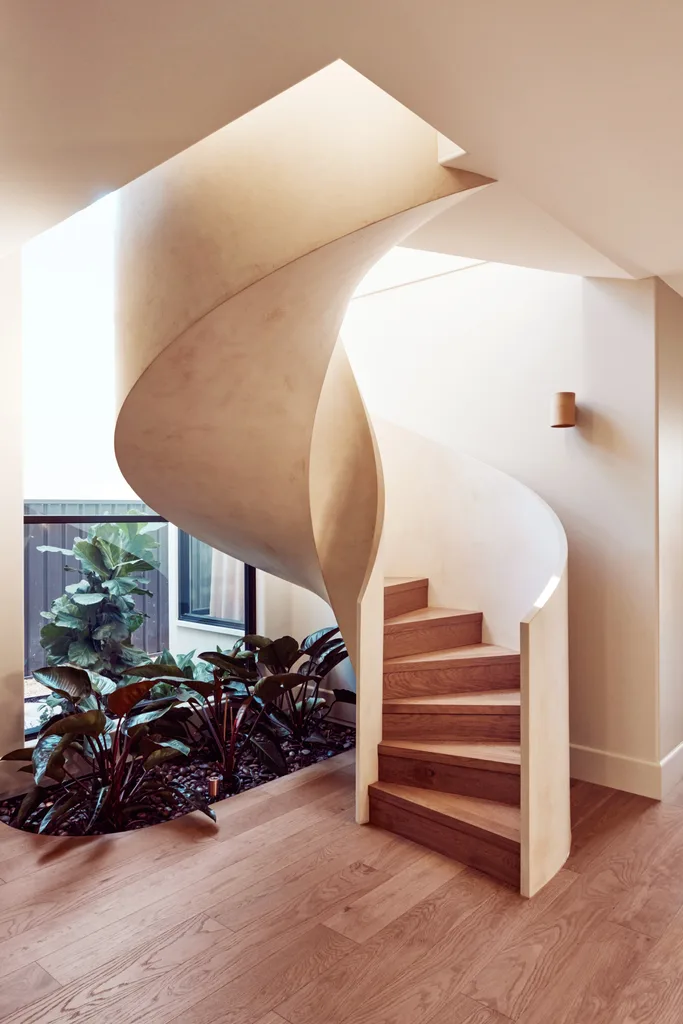 A curved staircase above a small indoor planter.