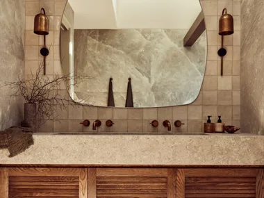 A main bathroom with rock salt tiles and a wooden floating vanity topped with stone.