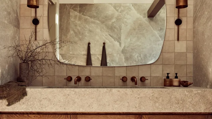 A main bathroom with rock salt tiles and a wooden floating vanity topped with stone.