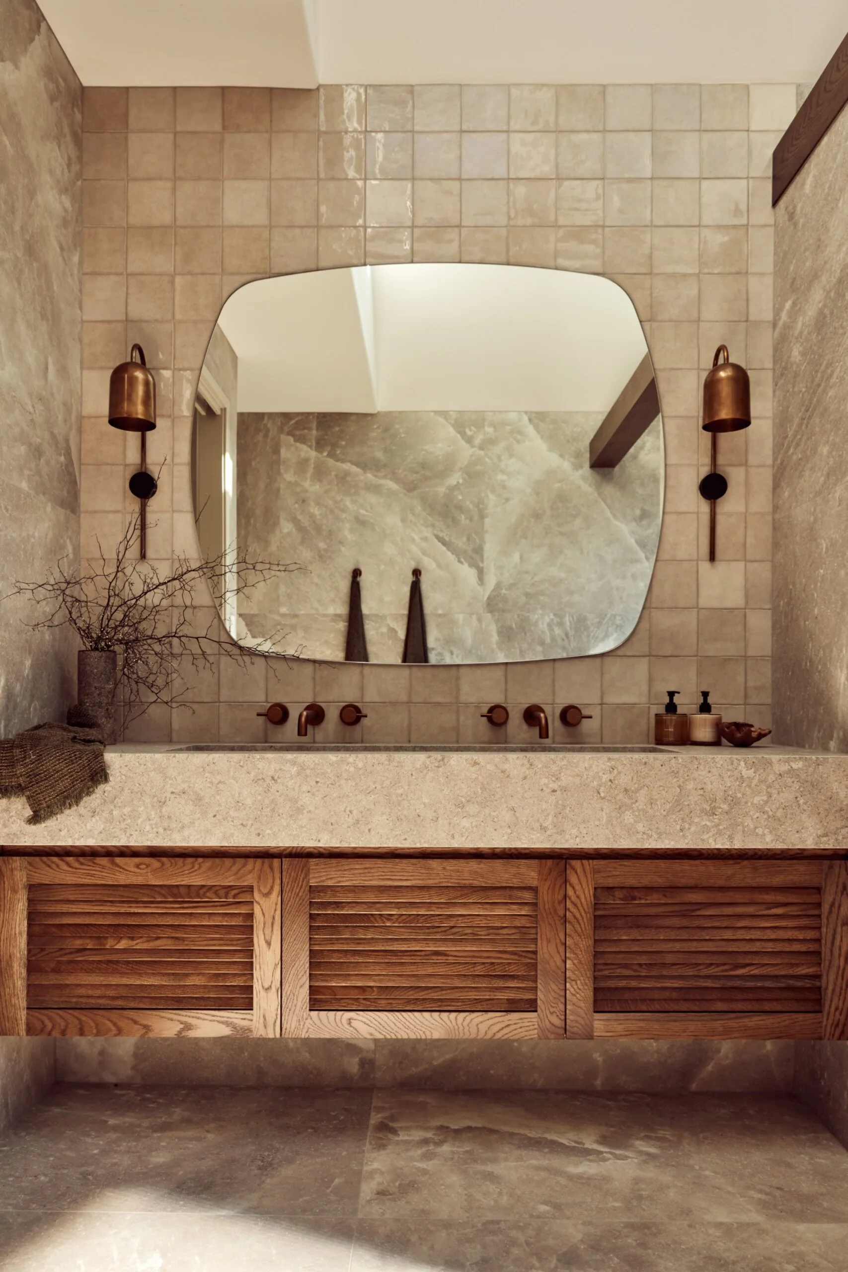 A main bathroom with rock salt tiles and a wooden floating vanity topped with stone.