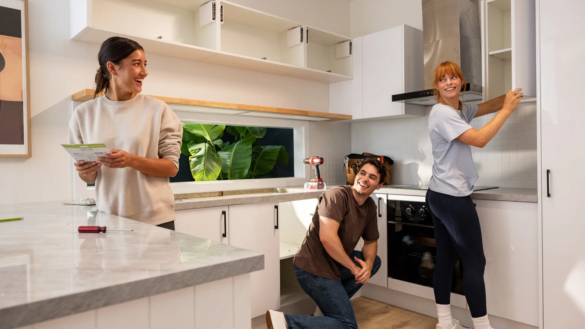 Three people doing DIY in the kitchen