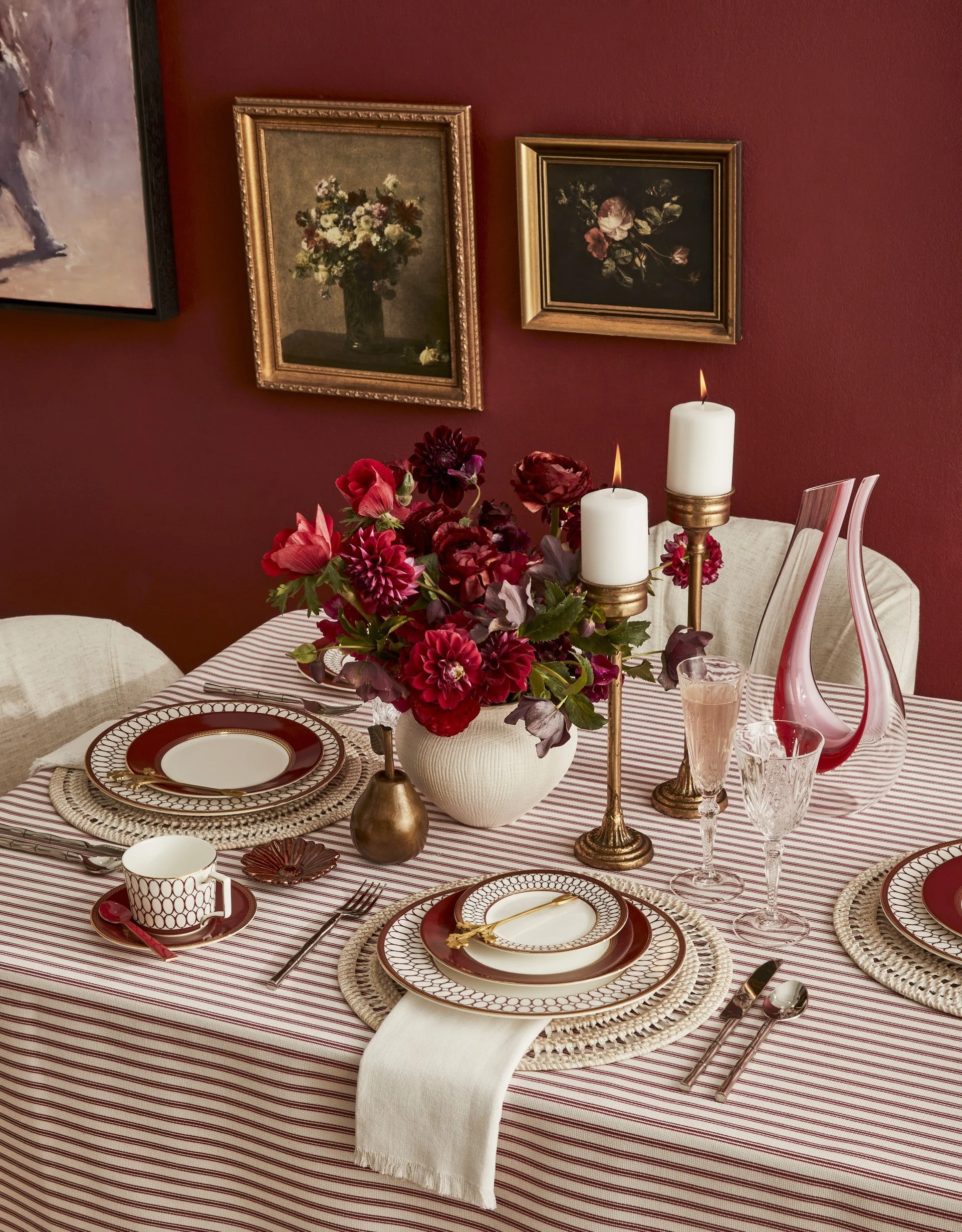 Red and white striped tablecloth with white, red and golden tableware, beside a red wall