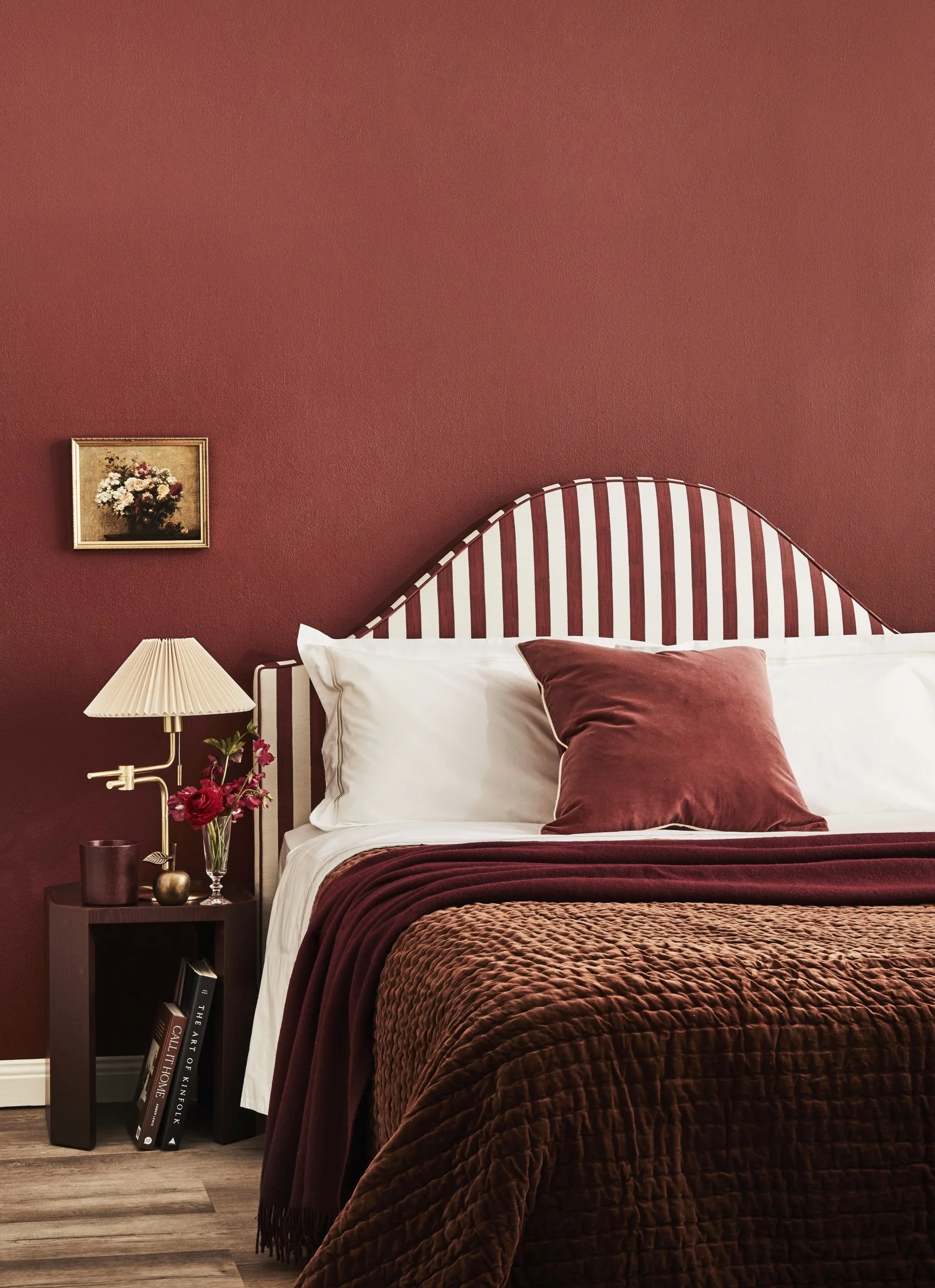 White and red bedhead with layers of red and white linen on top, in front of a red wall