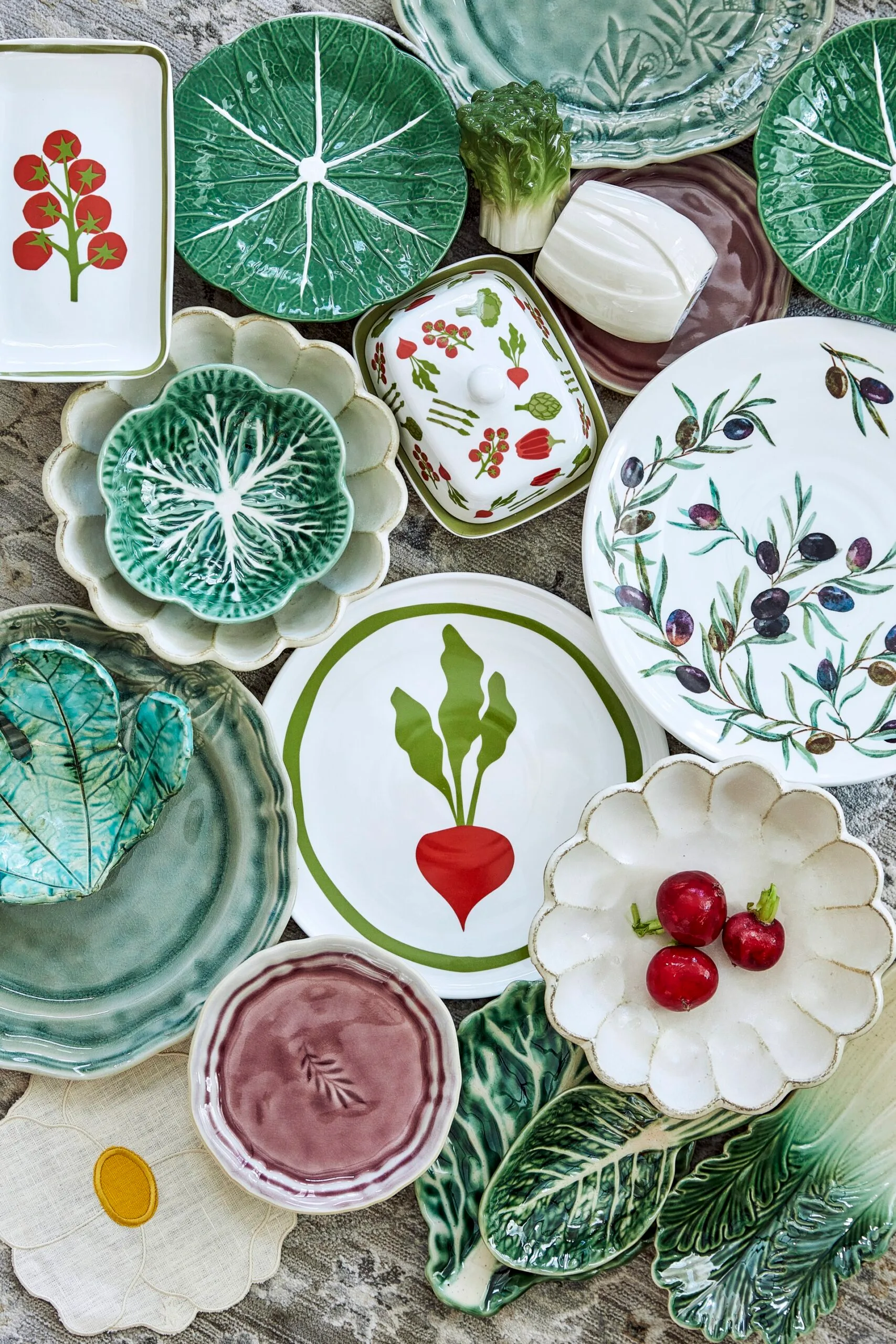 A collection of plates with various botanical motifs, including cabbageware, plates with olive patterns and radish patterns, all perfect for a garden inspired kitchen