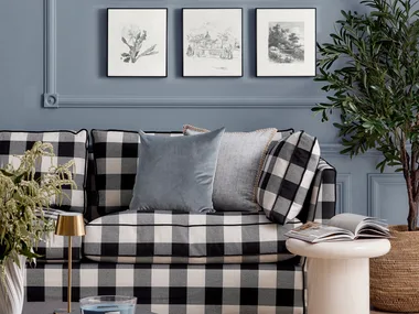 Black and white chequered couch in front of a blue wall with black and white artworks arranged in a grid pattern