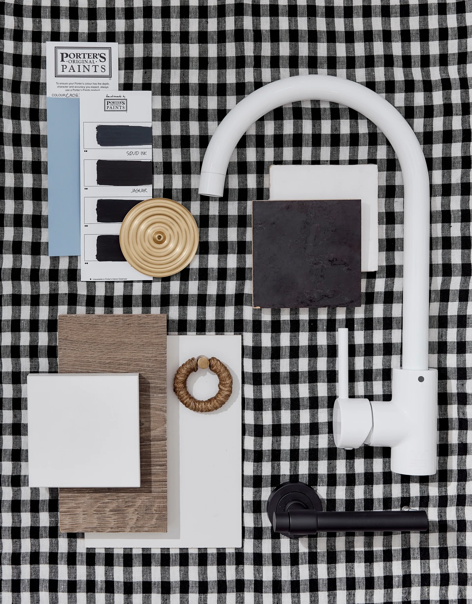 A black and white gingham cloth has a moodboard on top of it, with black and white swatches.