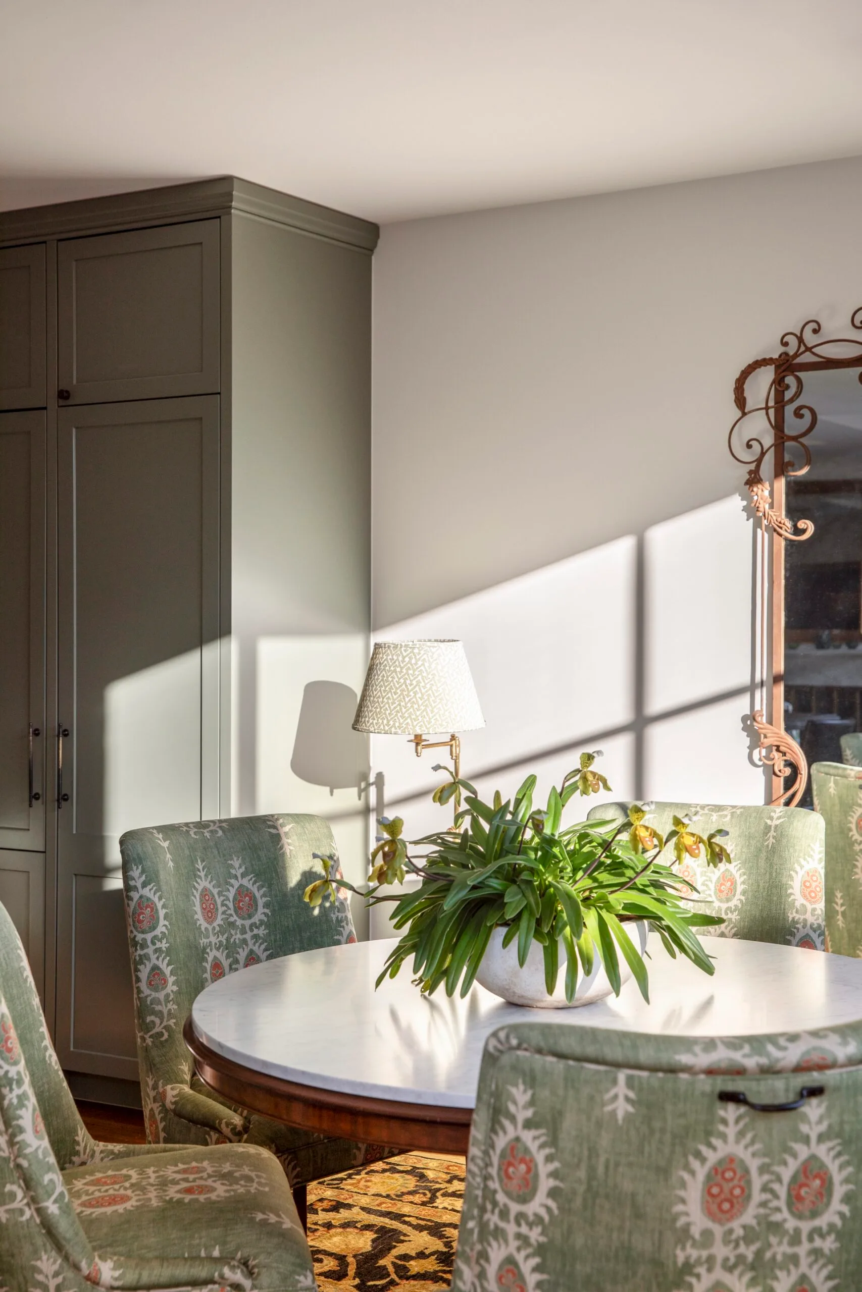 A circular dining table and green dining chairs. 