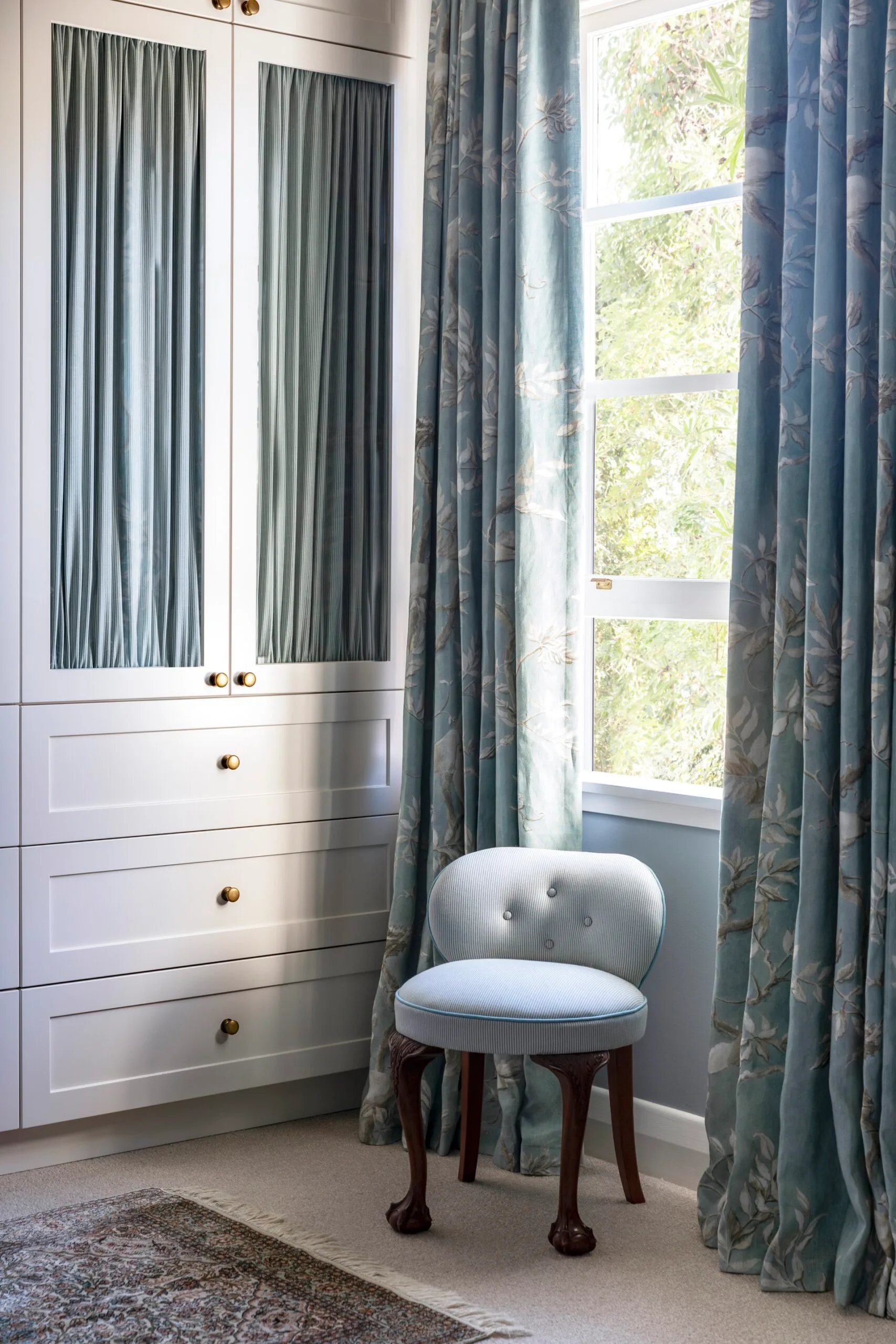 A white wardrobe with striped blue curtains in South Yarra. 