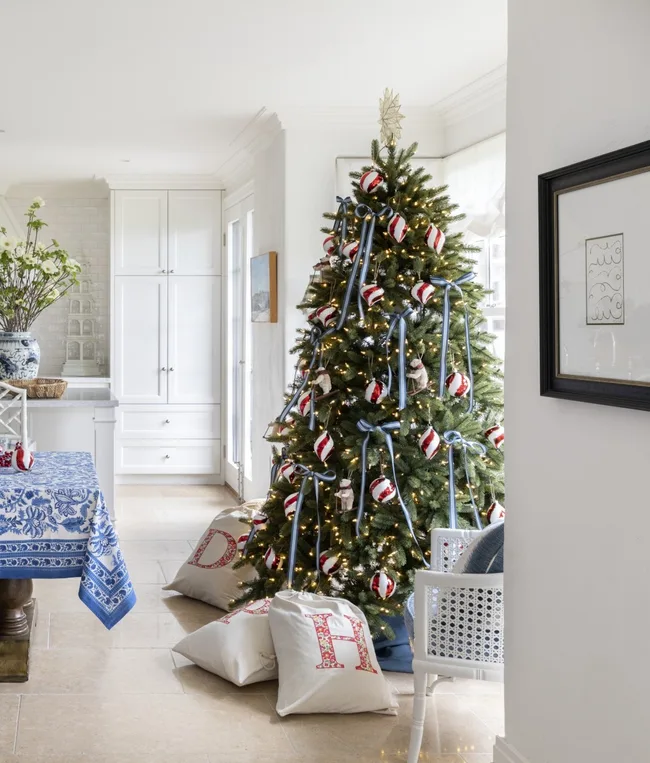 Red and white candy cane striped baubles decorate this Christmas tree beside blue ribbons and ornaments in the shape of polar bears