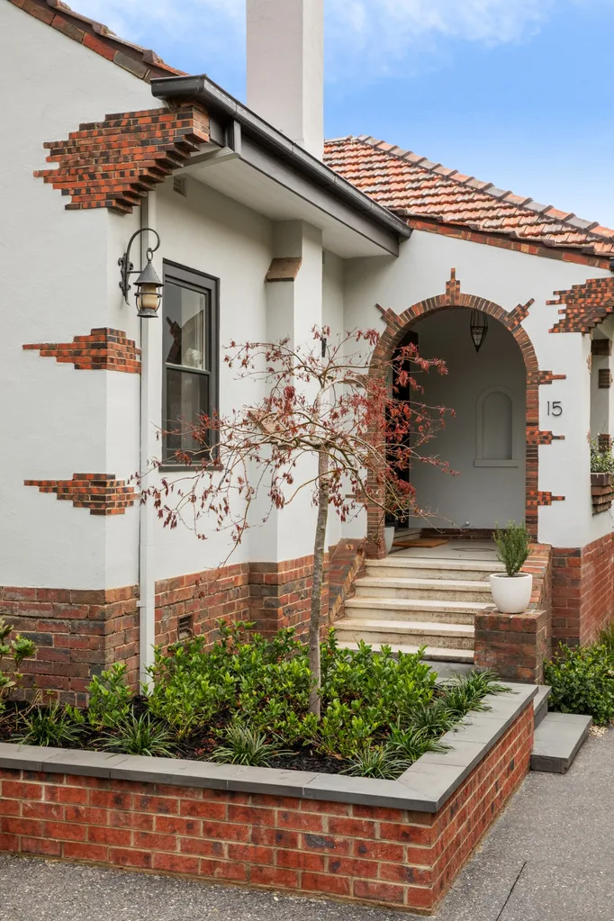 Red-brick arched entrance of a house, with a decorative tree and number 15 on the wall.