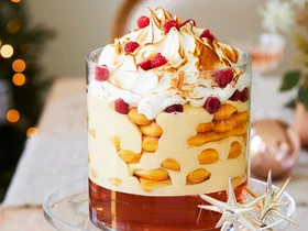 Rose and zabaglione trifle recipe served in a tall glass cylinder atop a glass cake stand with Christmas decorations