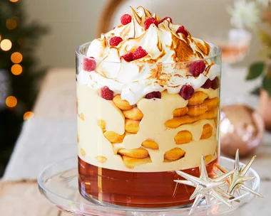 Rose and zabaglione trifle recipe served in a tall glass cylinder atop a glass cake stand with Christmas decorations