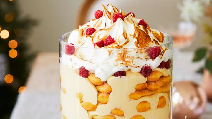 Rose and zabaglione trifle recipe served in a tall glass cylinder atop a glass cake stand with Christmas decorations