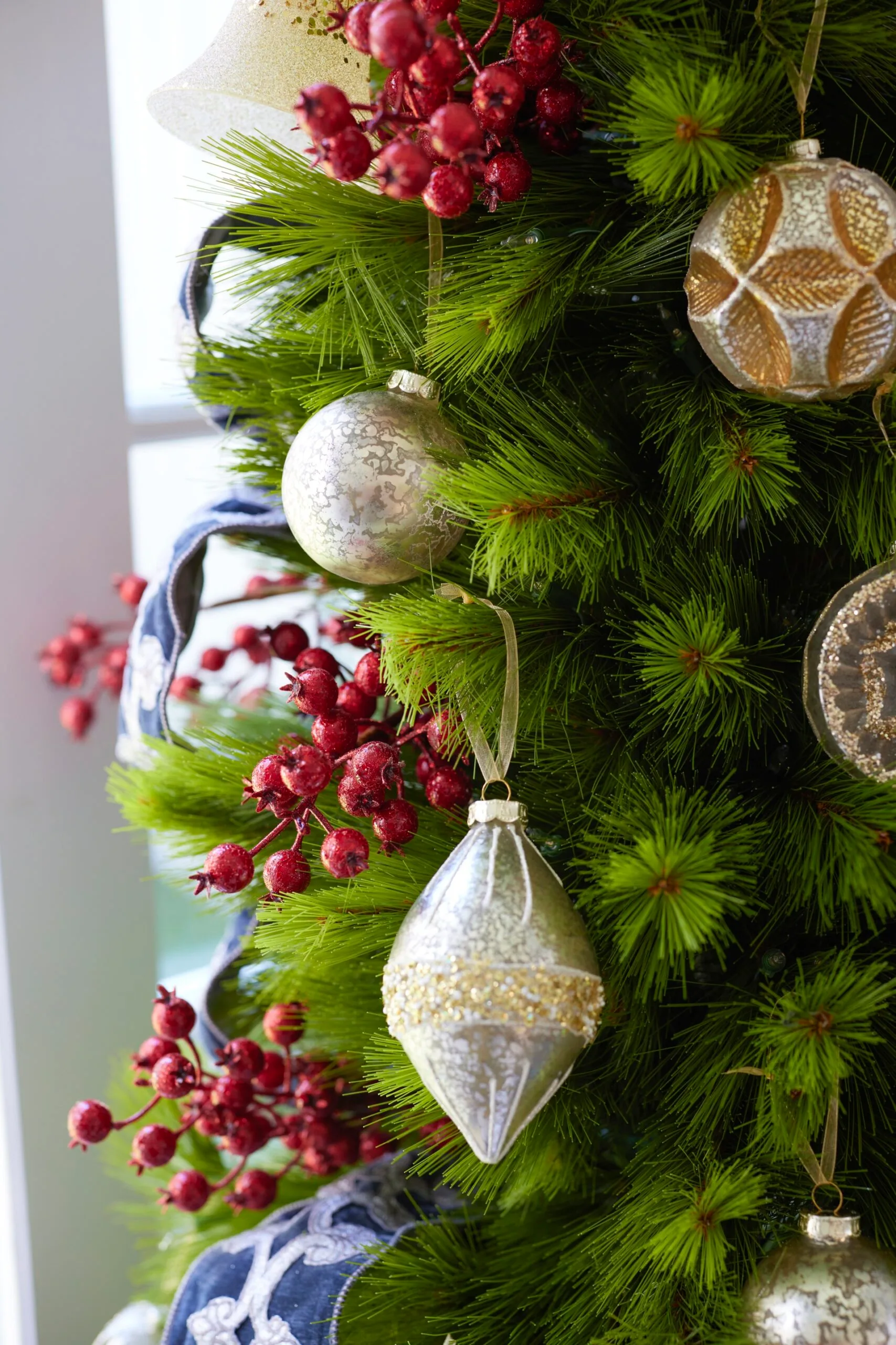 Christmas tree with silver and gold ornaments and red berries used as decoration