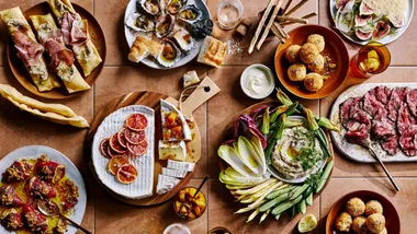 overhead shot of entertaining food table with cheese, crudite, arancini and oysters