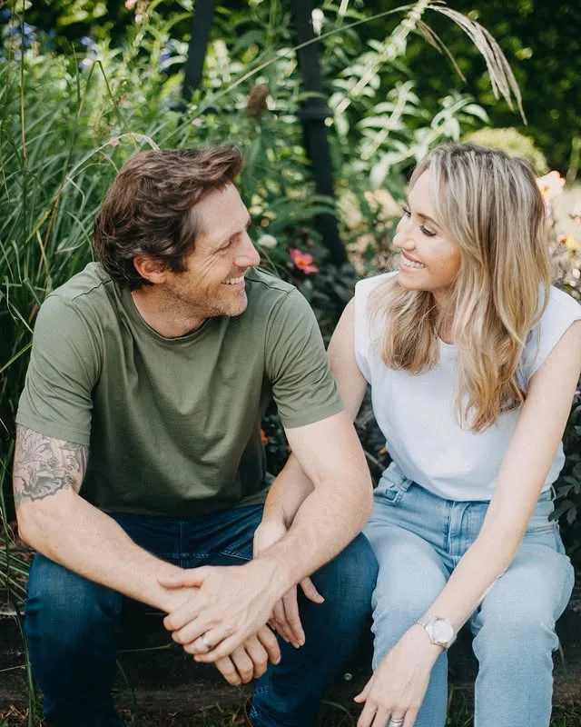 Charlie Albone and Juliet Love smiling and looking at each other